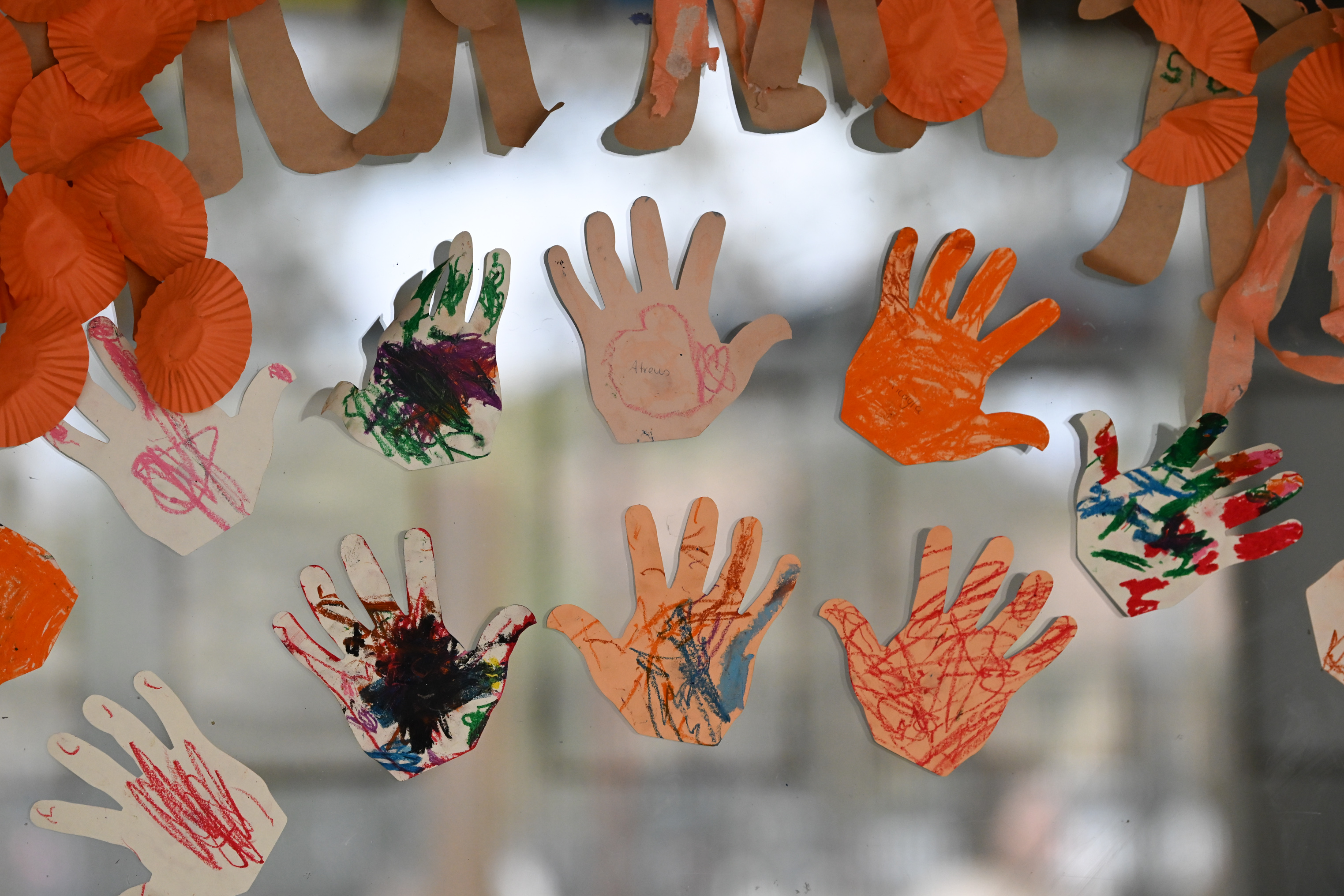 A photo of children's paper hand prints displayed on a window