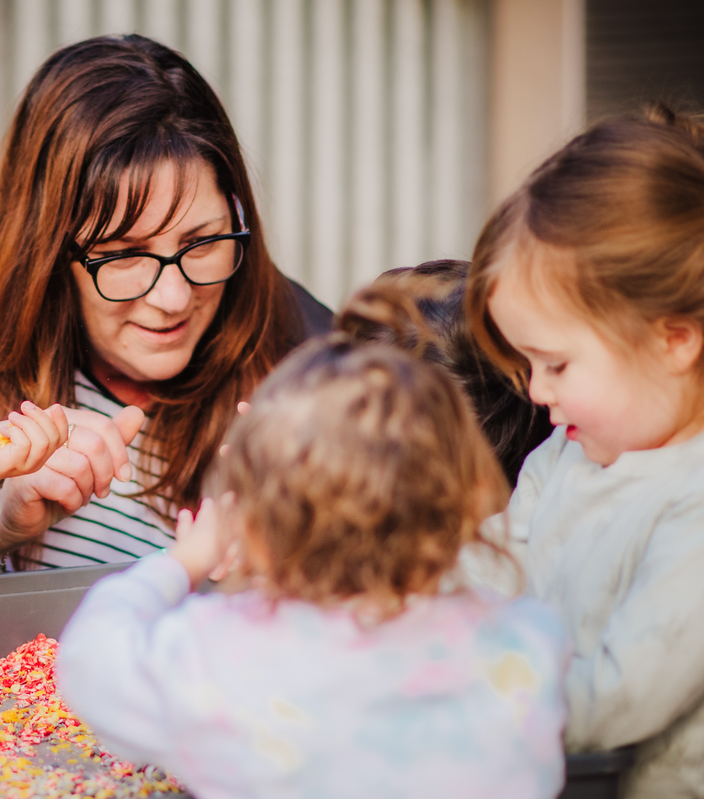 An educator plays with a group of children at a tough tray