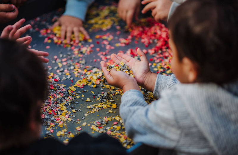 Children around a tray with a sensory confetti activity
