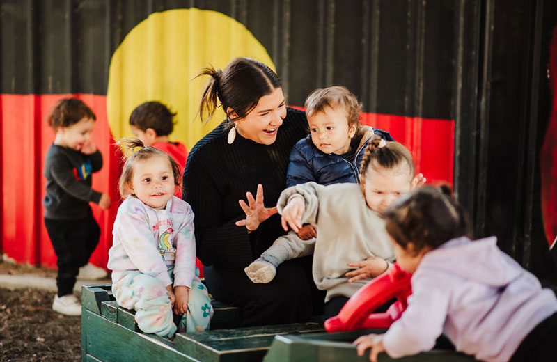 An educator surrounded by children at a preschool