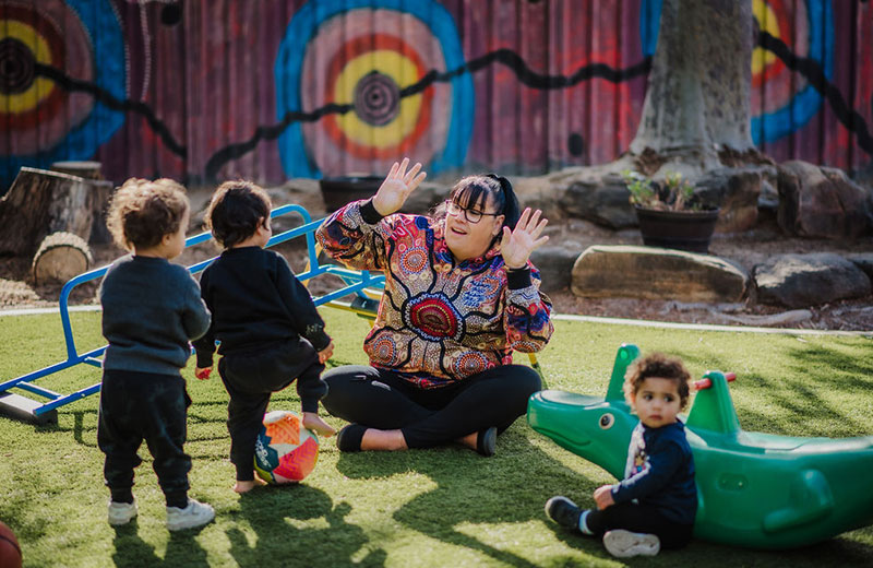 An educator surrounded by children at a preschool