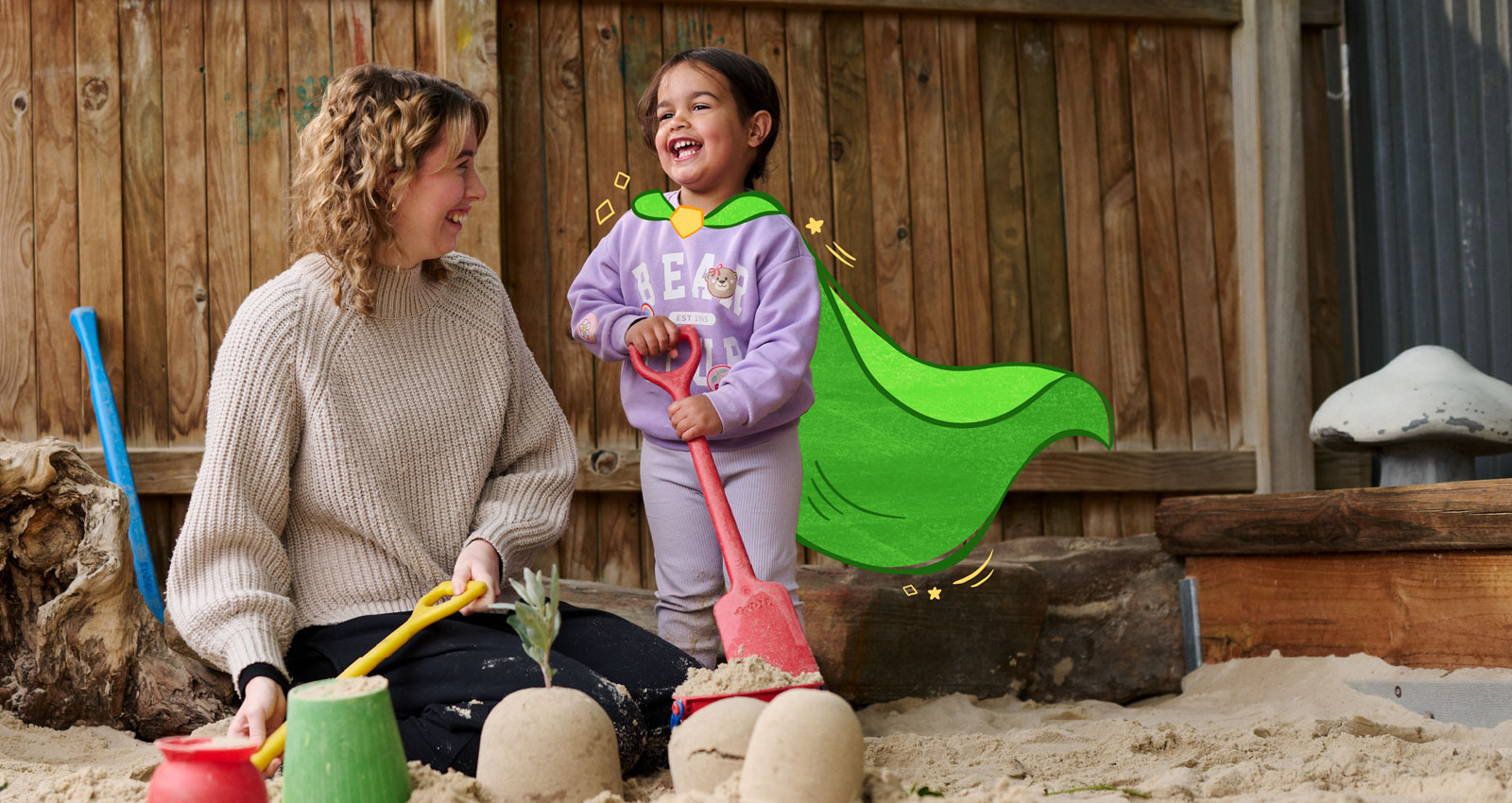 Child and educator smiling and digging, playing in a sandpit